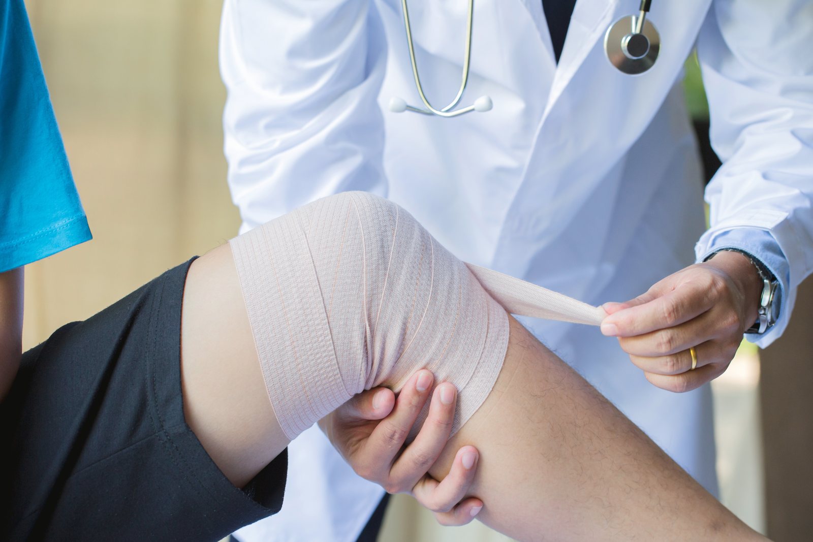 Hände messen und legen eine Bandage am Knie an