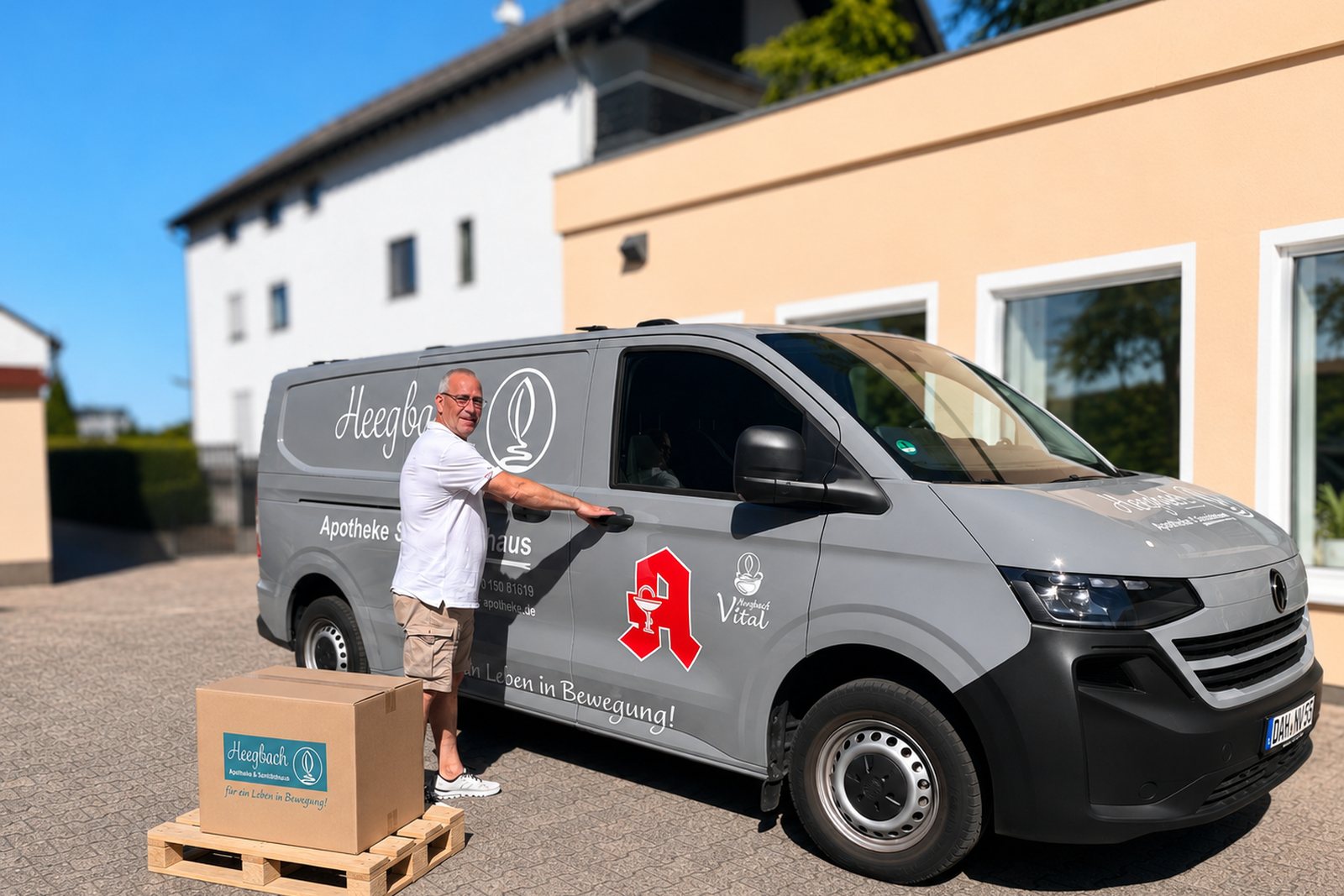 Mitarbeiter des Heegbach Sanitätshauses öffnet die Tür des beschrifteten Lieferwagens, davor ein Paket auf einer Palette